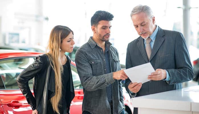 Man and woman talking to car salesman