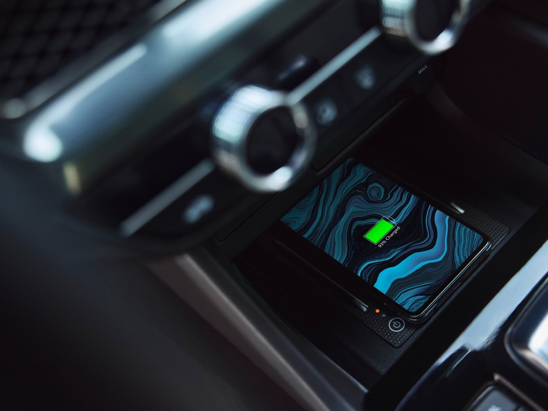 A phone wirelessly charging on the console of an Acura Integra