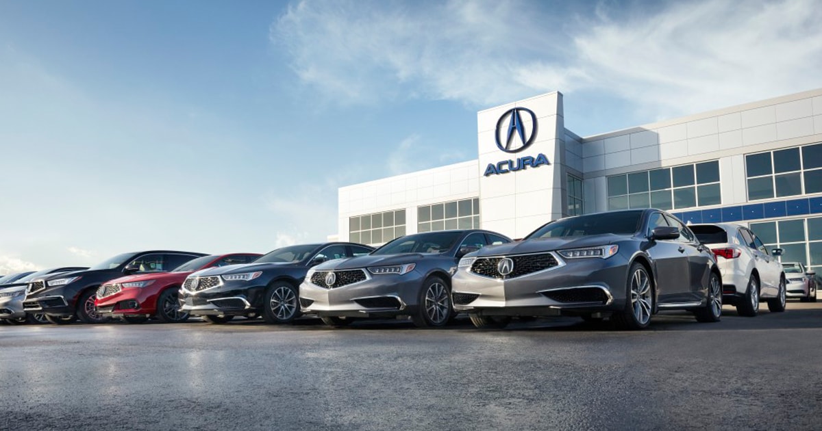 Acura model lineup parked infront of an Acura car dealership