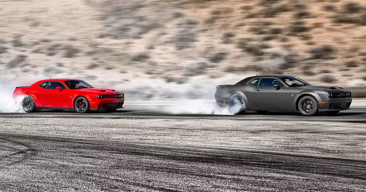 A red and a grey Dodge Challenger racing through a desert