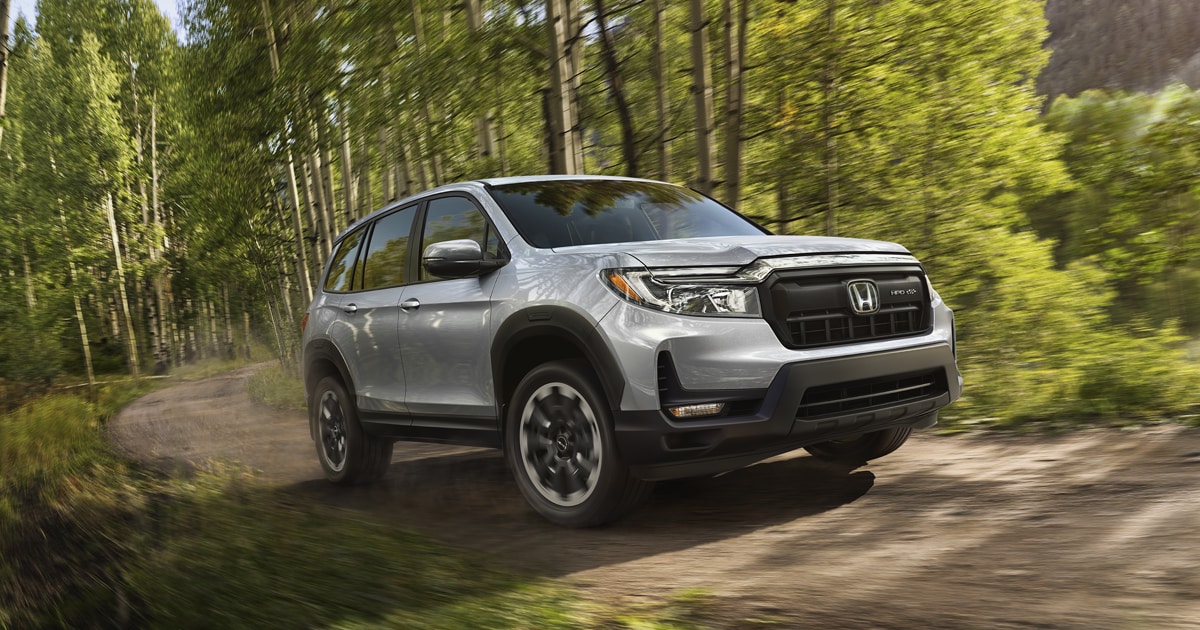 Silver Honda Passport driving off-road through a park