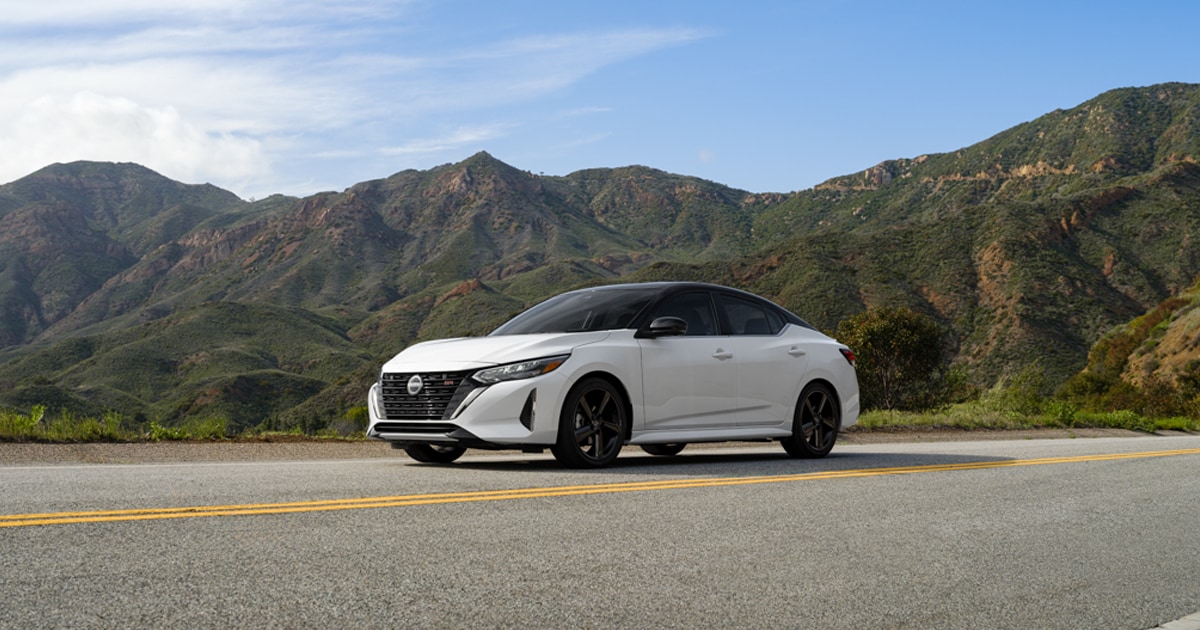 A Nissan Sentra parked on a road by a mountains