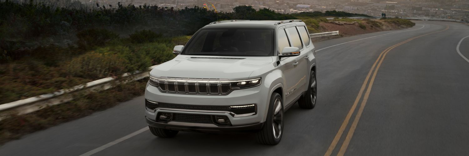Grand Wagoneer driving on rural road with sunset behind it