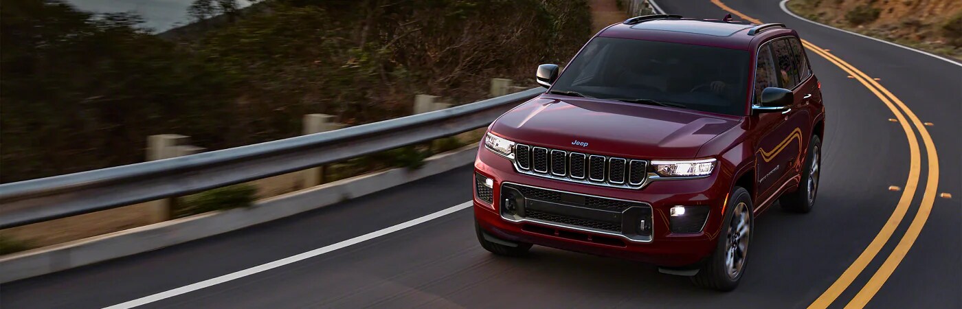red jeep grand cherokee driving down curvy road