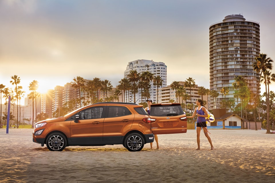 orange Ford EcoSport SUV parked on the beach with the trunk open