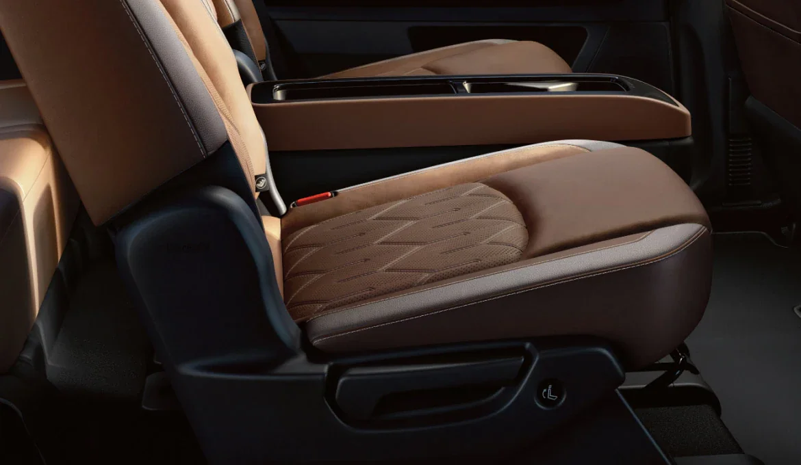Close-up of a Nissan Pathfinder second-row seat in perforated brown leather with the slide and tilt release handle at the base of the cushion