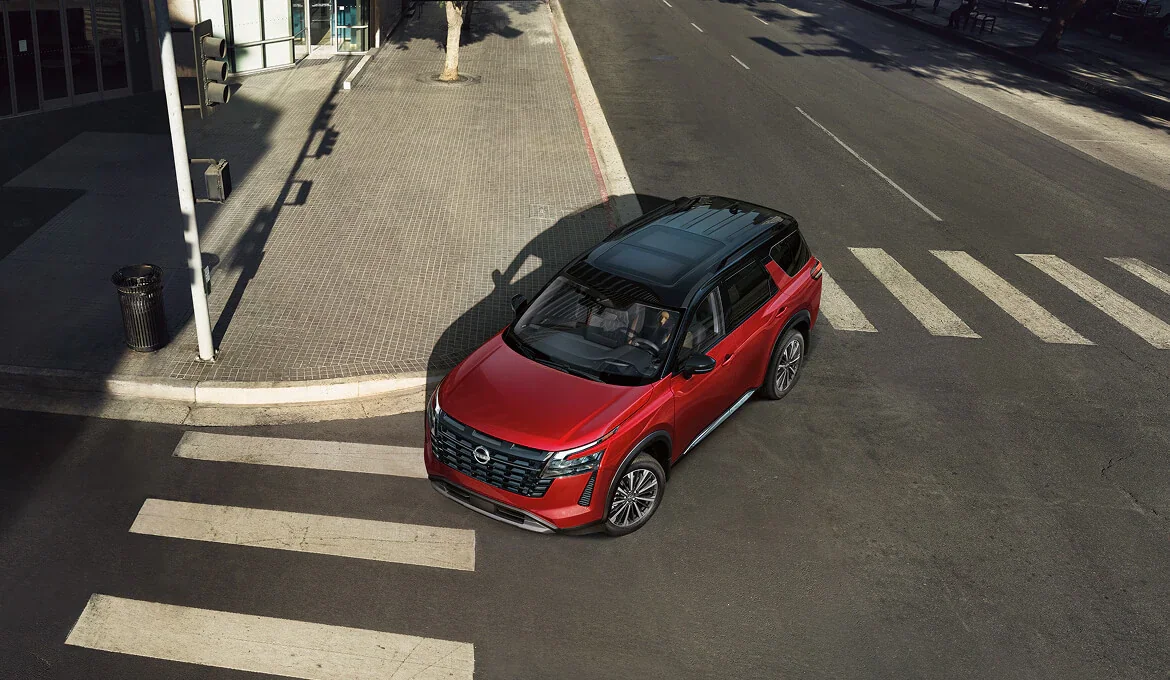 Red Nissan Pathfinder crossing a city intersection, viewed from above