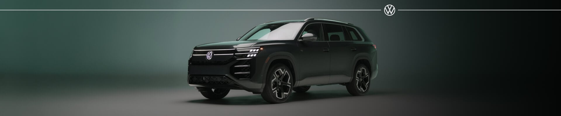 Volkswagen Atlas SEL Premium R-Line in Sacramento Green Metallic with full LED front lighting inside a studio setting.