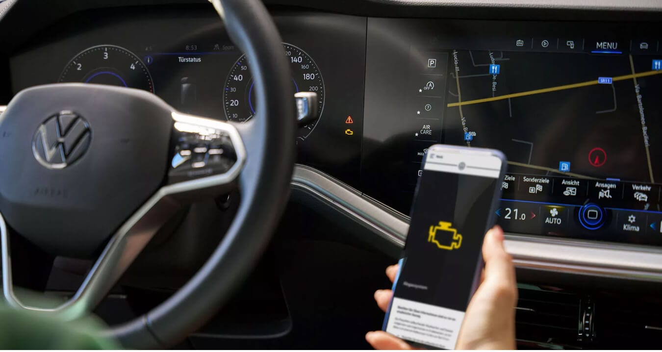 Volkswagen Golf interior in Soul Black Cloth/ArtVelours with digital cockpit display showing smartphone engine warning app.