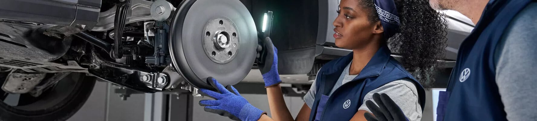 Volkswagen technicians inspecting the undercarriage of a Volkswagen vehicle