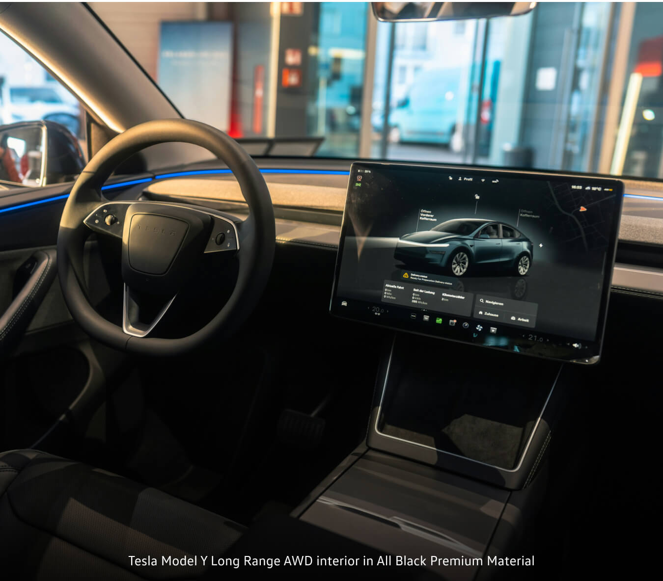 Tesla Model Y Long Range interior in All Black displaying central touchscreen inside a dealership showroom.