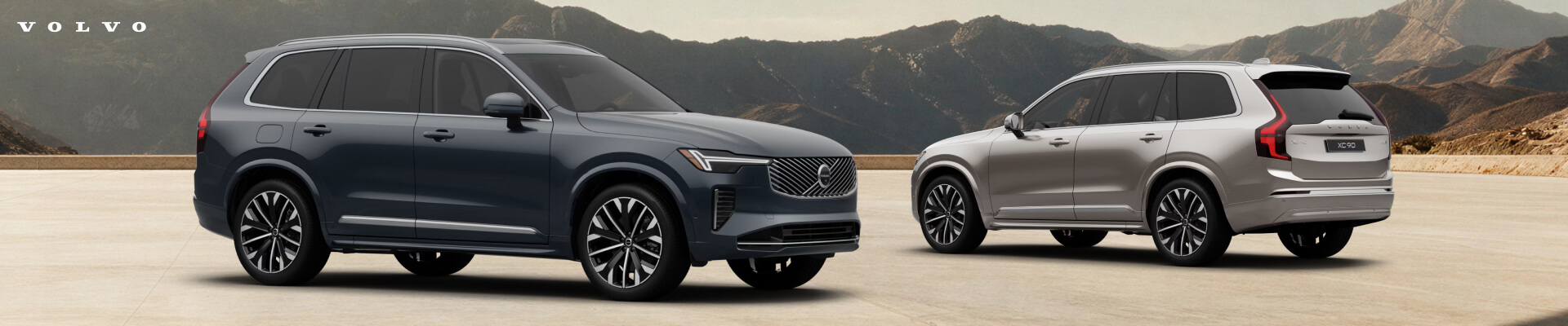 2026 Volvo XC90 Ultra front and back three-quarter view in Denim Blue and Bright Dusk, parked against a mountain backdrop.