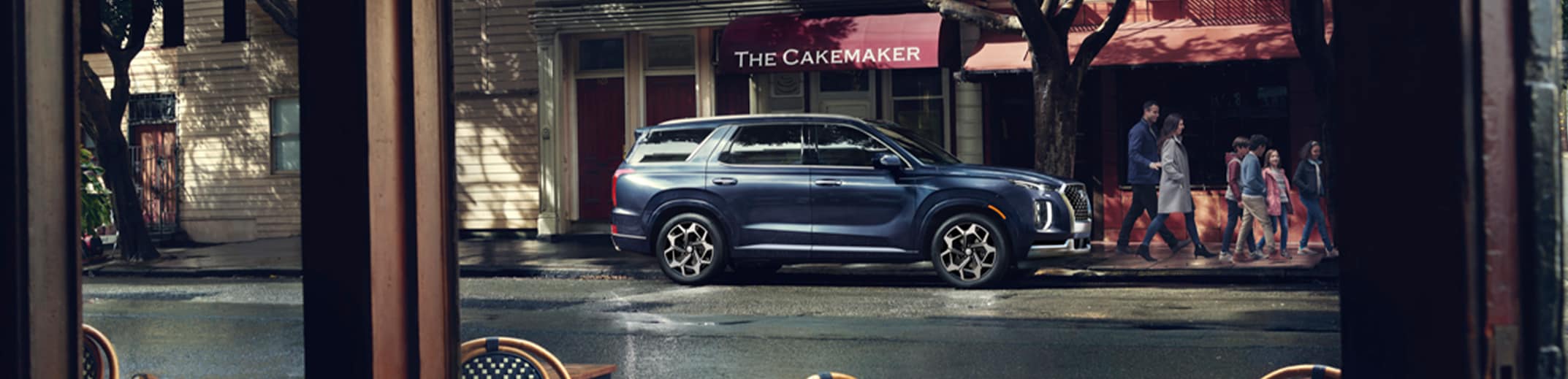 Haddad Hyundai is a Hyundai Dealership  near Pittsfield, MA | Navy blue Hyundai Palisade parked outside on the side of the street with a family walking by it