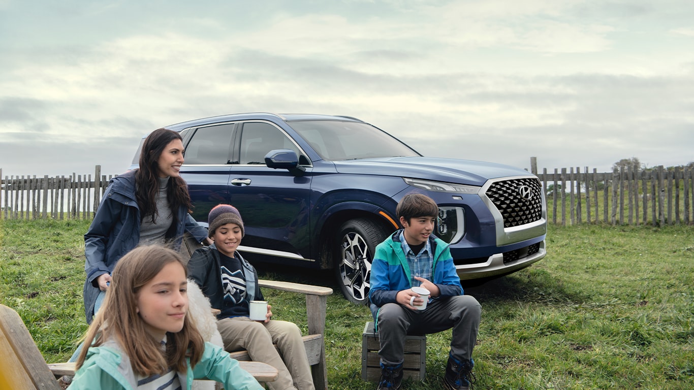 Haddad Hyundai Dealership near North Adams, MA | Kids and their mother sitting in front of a navy blue Hyundai Palisade