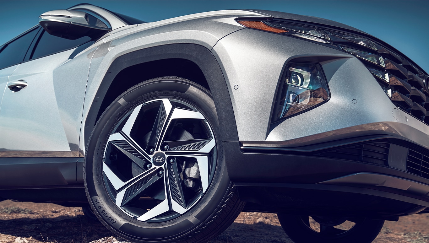  2023 Hyundai Santa Fe at Haddad Hyundai | White 2023 Hyundai Santa Fe driving on dirt road with bike rack on the roof 