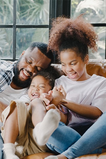 Defining GAP Insurance at Haddad Hyundai in Pittsfield, MA | Father and his two children smiling and playing around on the couch at home