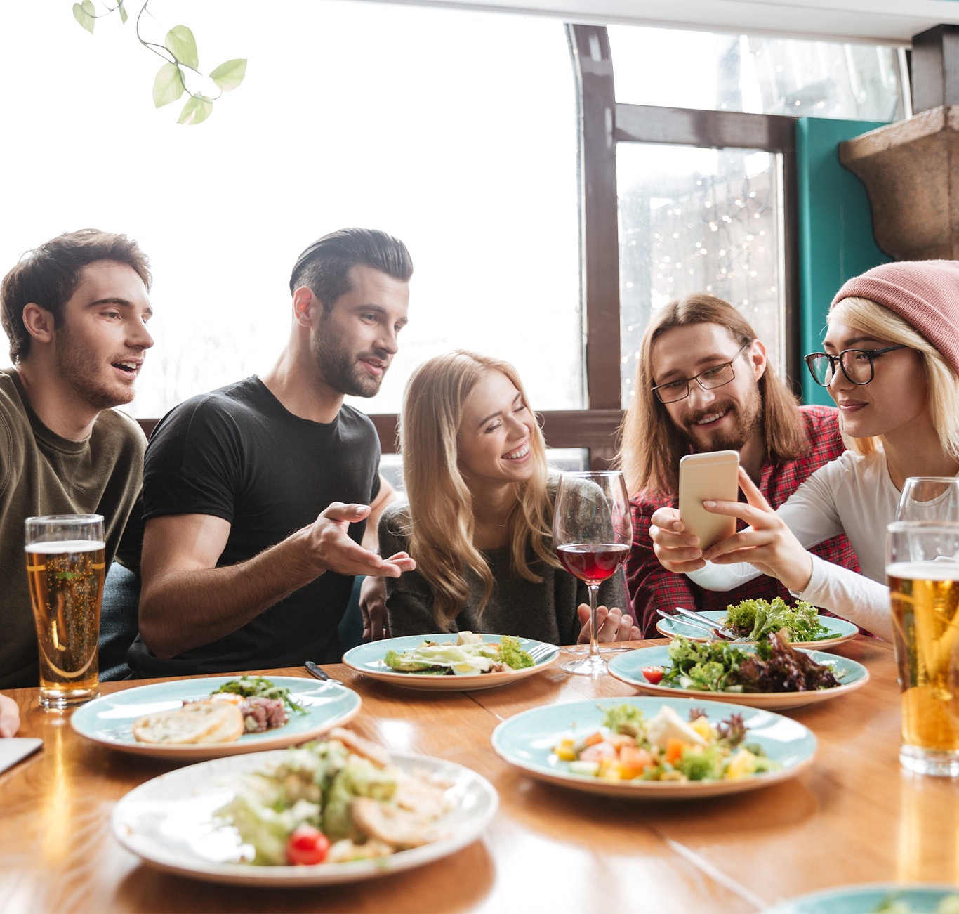 Haddad Hyundai is a Hyundai Dealership  near Pittsfield, MA | Group of friends eating and having drinks while one friend is showing them something on her phone 