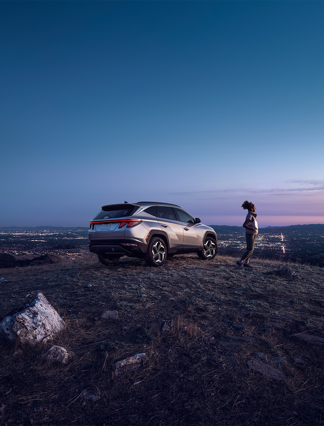  2023 Hyundai Santa Fe at Haddad Hyundai | Side profile of a white 2023 Hyundai Santa Fe driving up the side of a hill 