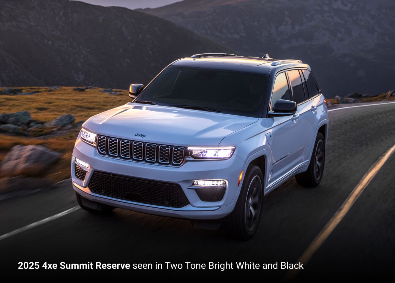 2025 Jeep Grand Cherokee 4xe Summit Reserve in two-tone Bright White and Black, front three-quarter view on a mountain road.