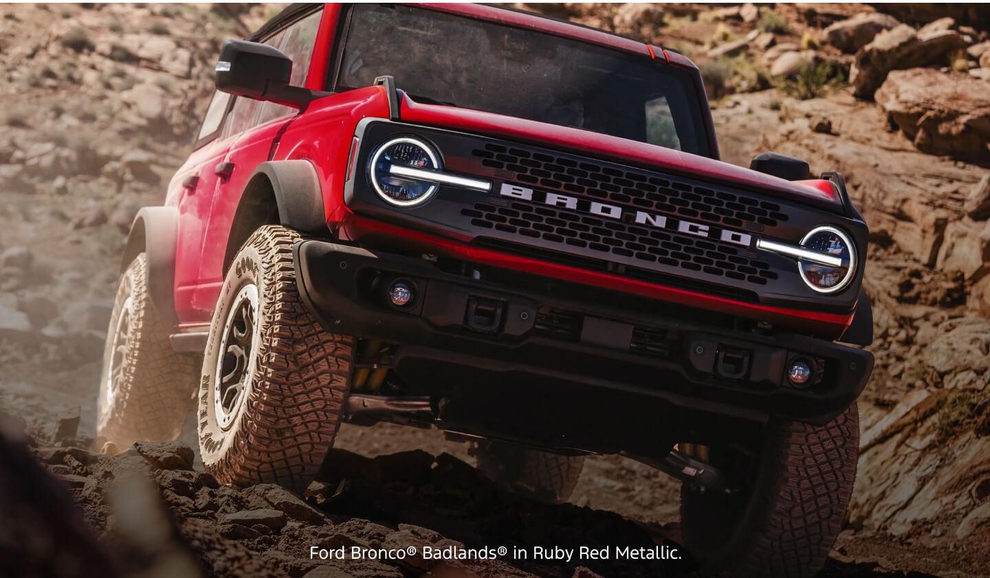 Front low-angle view of a red Ford Bronco Badlands navigating a steep, rocky mountain trail.
