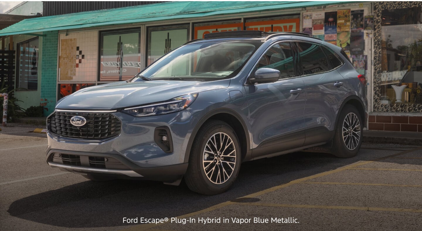 Three-quarter front view of a blue Ford Escape Plug-In Hybrid parked outside a retro storefront location.