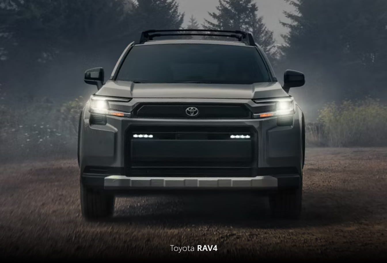 Gray Toyota RAV4 shown from the front with headlights illuminated on a misty forest road.