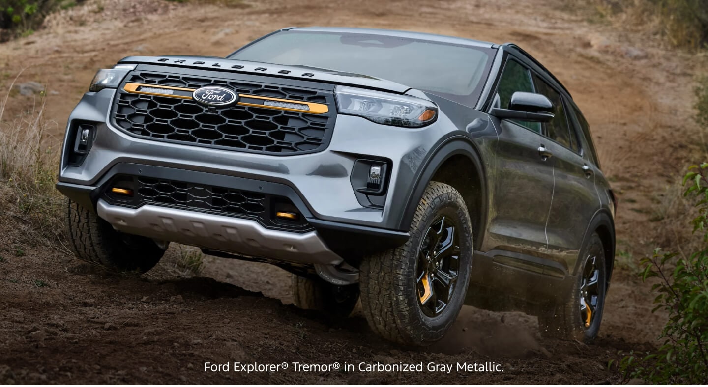 Front three-quarter view of a gray Ford Explorer Tremor navigating a rugged dirt hill path.