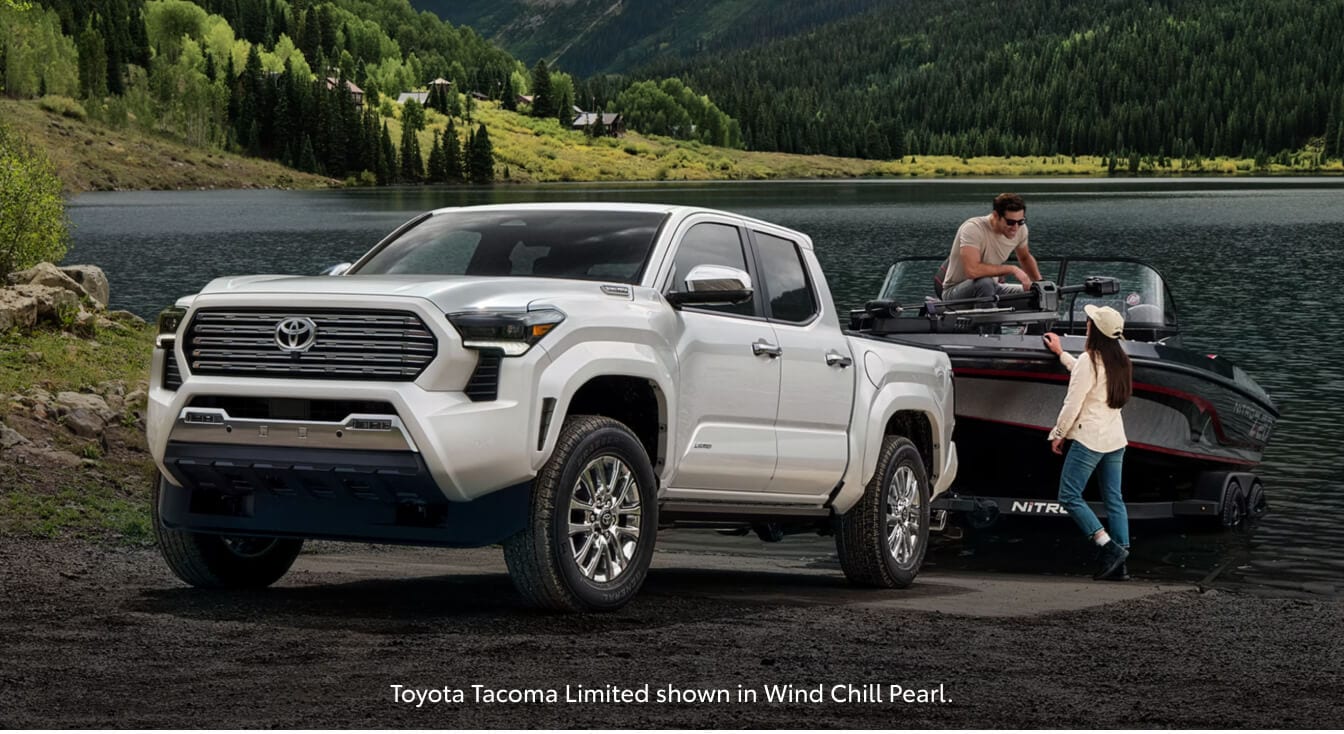 Three-quarter front view of a 26 Toyota Tacoma Limited towing a boat on a concrete ramp.