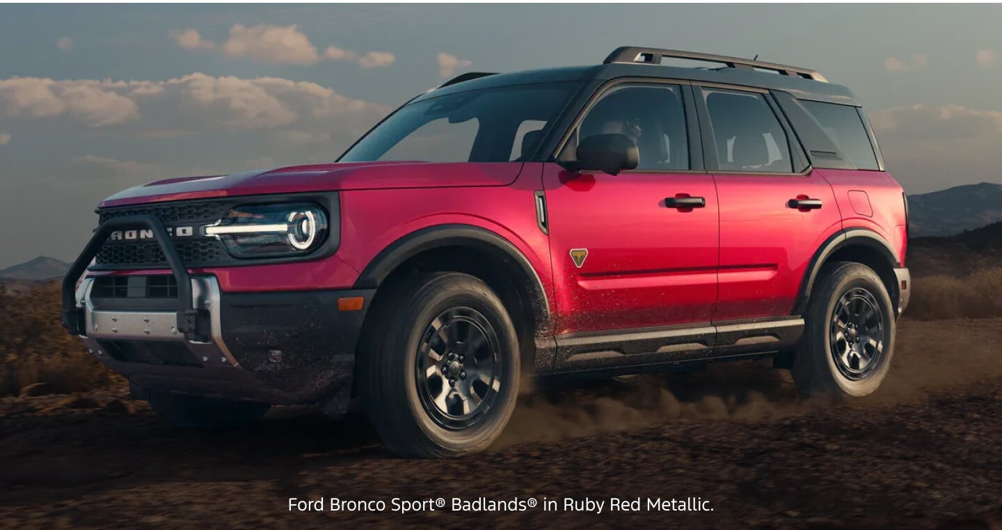 Three-quarter front view of a red Ford Bronco Sport Badlands i kicking up dirt on an off-road desert trail.