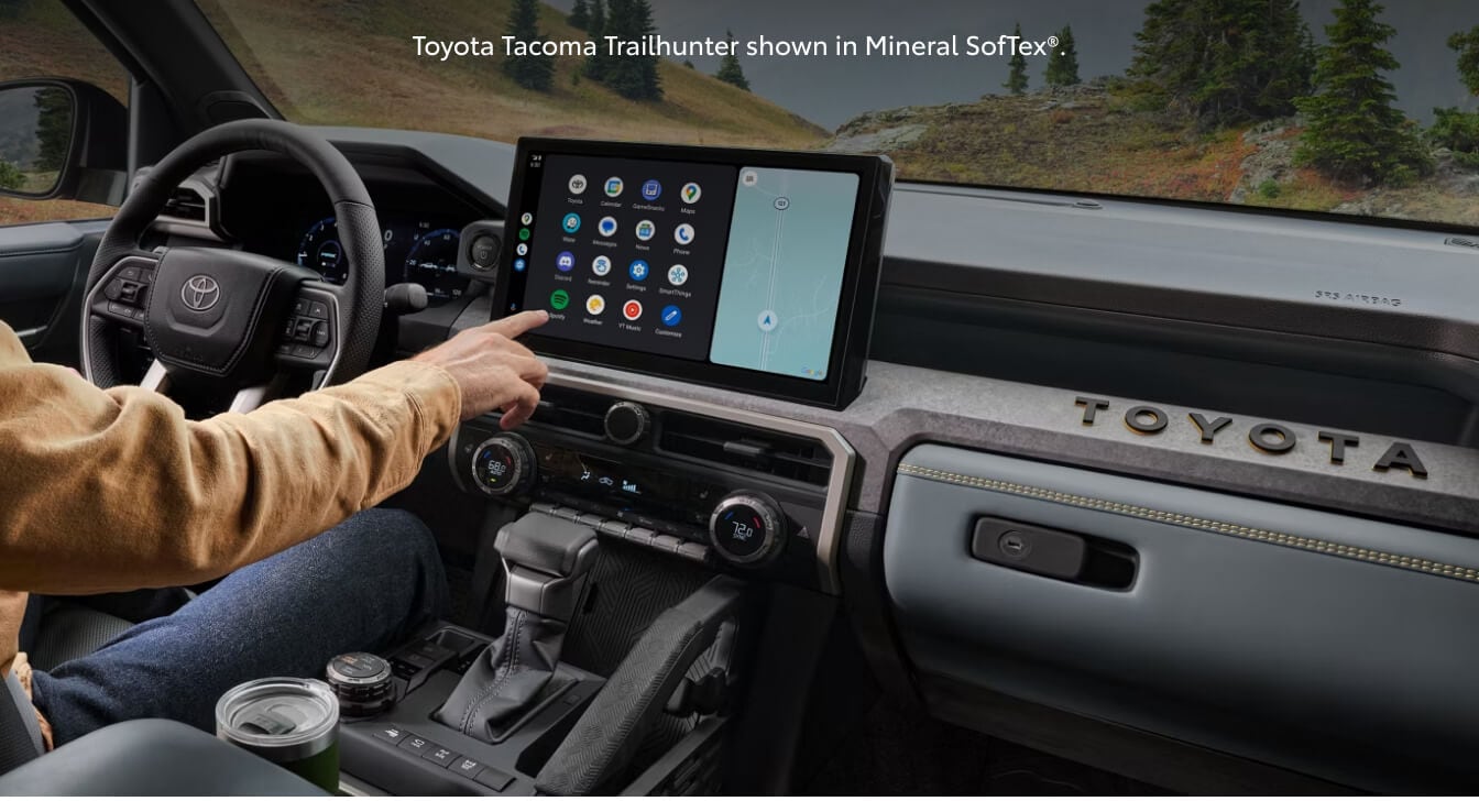 Close-up interior view of a 26 Toyota Tacoma Trailhunter as a driver interacts with the touchscreen.