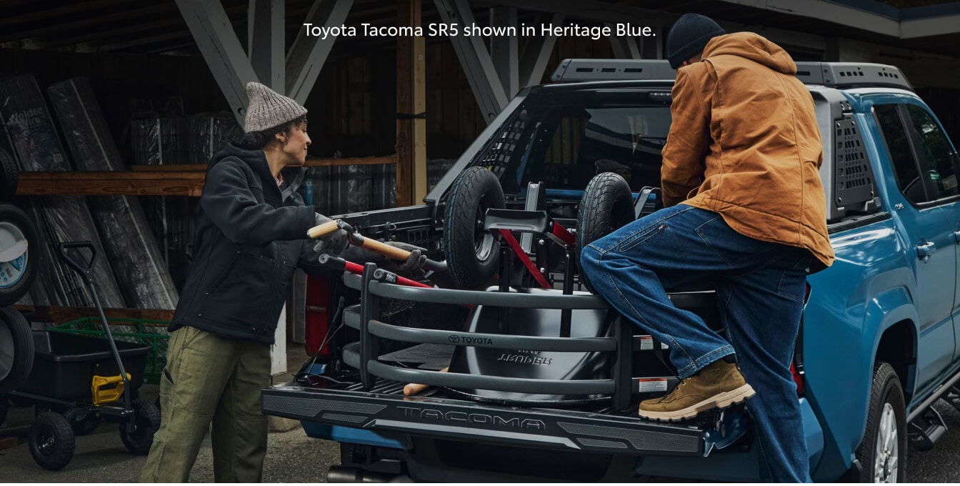 Rear view of a 26 Toyota Tacoma SR5 with an open tailgate as workers load equipment.