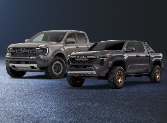 Three-quarter view of a 26 Ford Ranger Raptor and 26 Toyota Tacoma Trailhunter parked side-by-side.