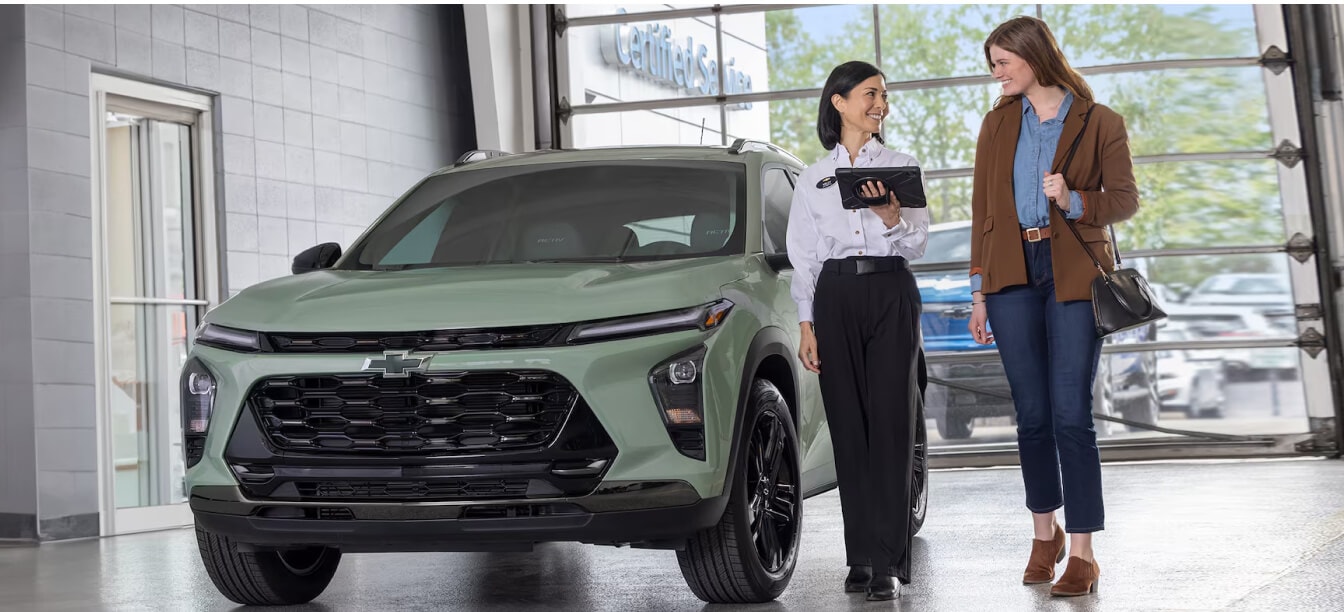 Chevrolet Trax ACTIV exterior in Cacti Green with service advisor showing a tablet to customer in dealership.