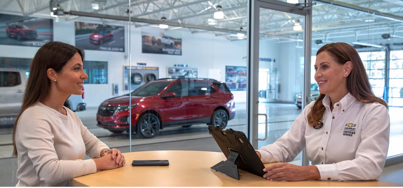 Chevrolet Equinox RS exterior in Radiant Red Tintcoat with showroom background showing a customer and service advisor.