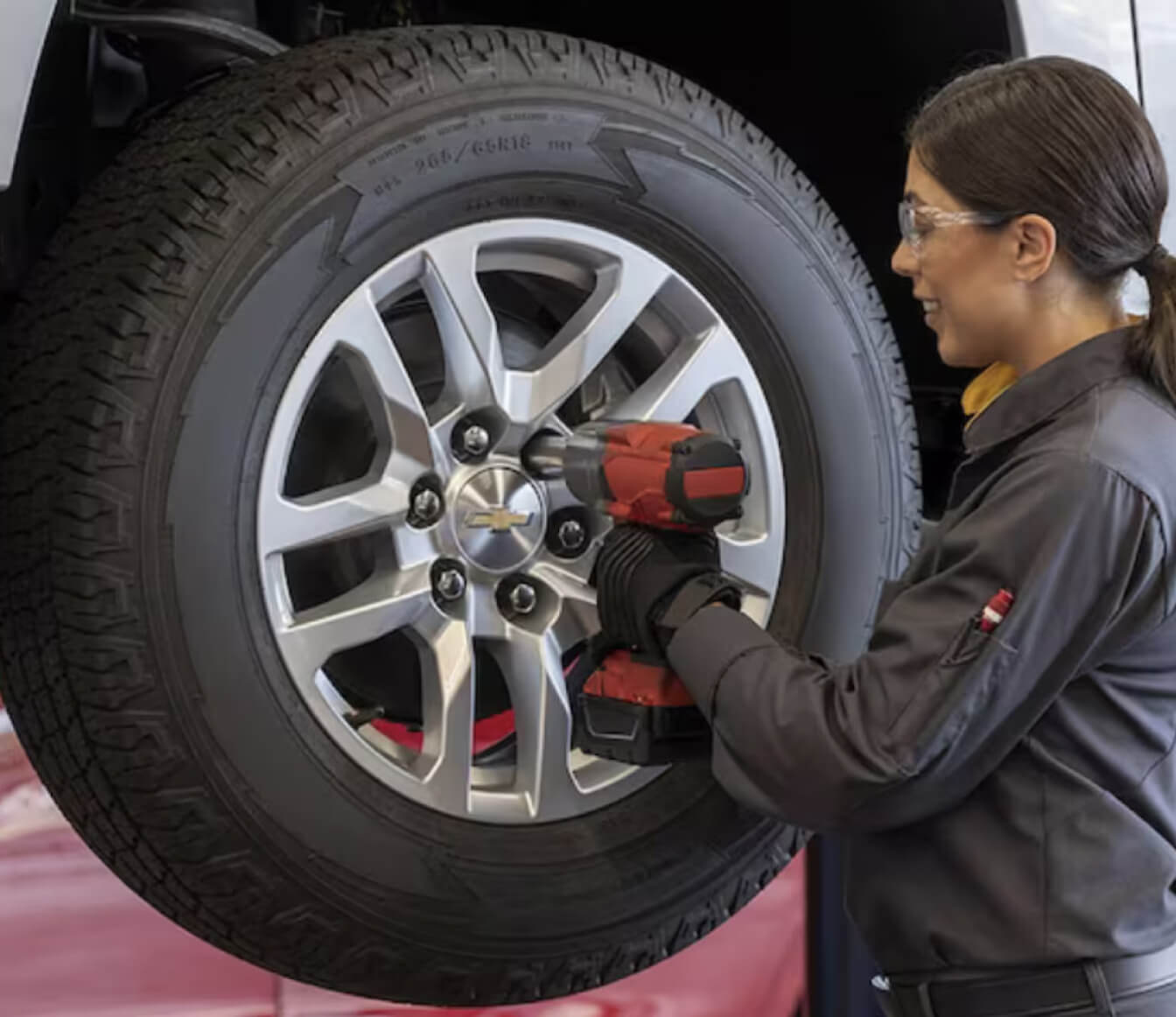 Chevrolet Silverado LT exterior in Sterling Gray Metallic with technician showing tire service on a vehicle lift.