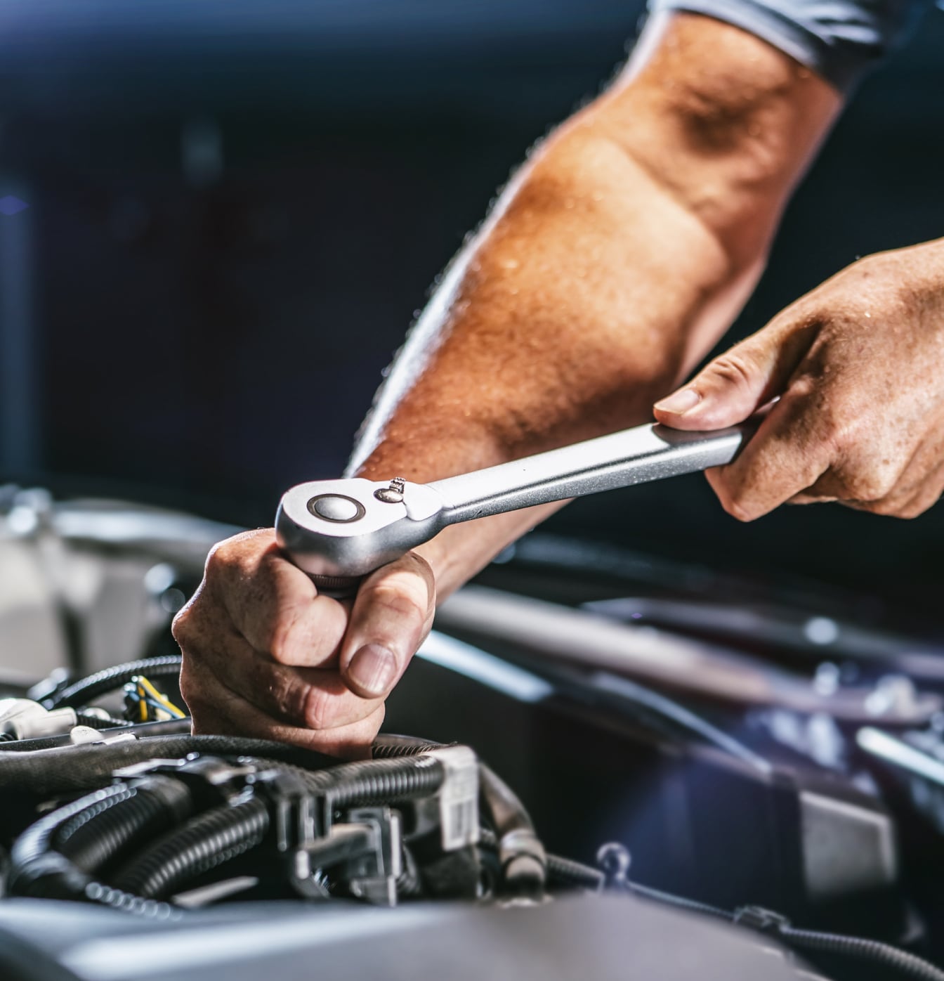 Mechanic using ratchet wrench on car engine