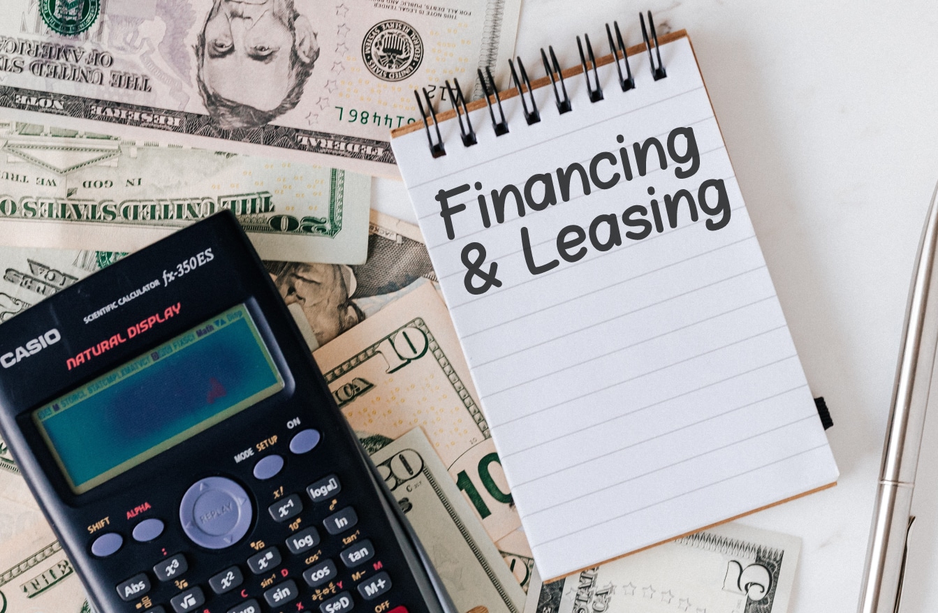 Calculator on money pile and notebook with "Financing and Leasing"
