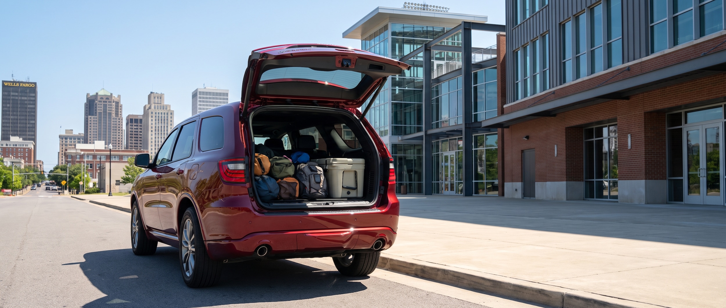 2026 Dodge Durango with open liftgate loaded with sports gear outside a Birmingham stadium on a summer afternoon