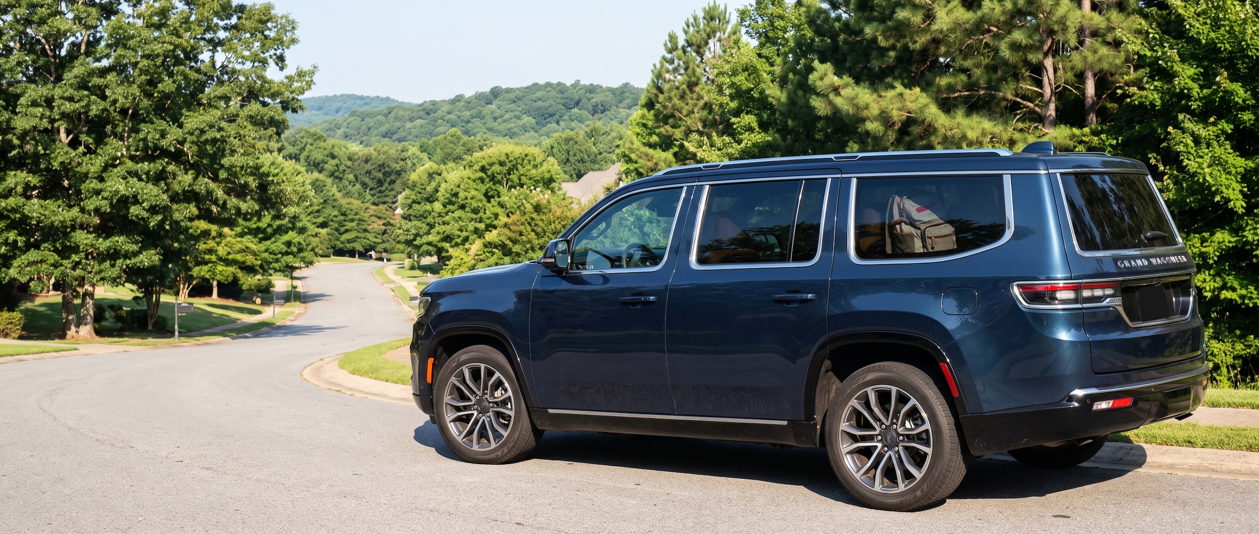 2026 Jeep Grand Wagoneer parked on hilly Vestavia Hills street, rear cargo loaded for the school run