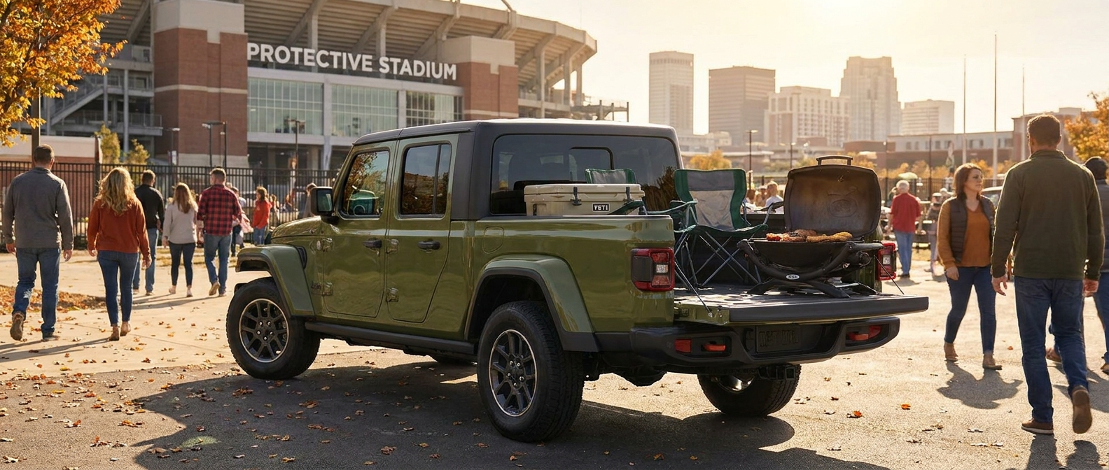 2026 Jeep Gladiator with tailgate down and tailgating gear loaded in the bed outside a Birmingham stadium