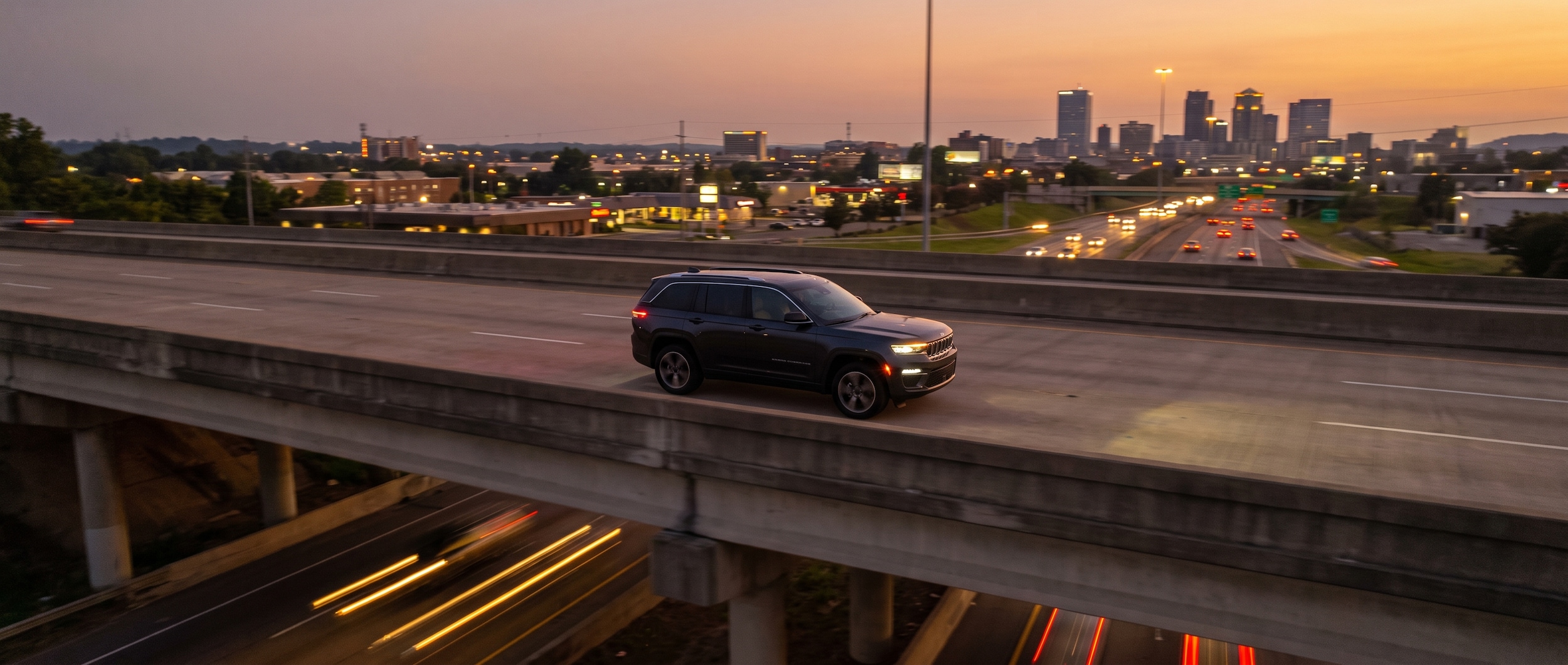 2026 Jeep Grand Cherokee on an elevated urban interstate at dusk in Birmingham, Alabama