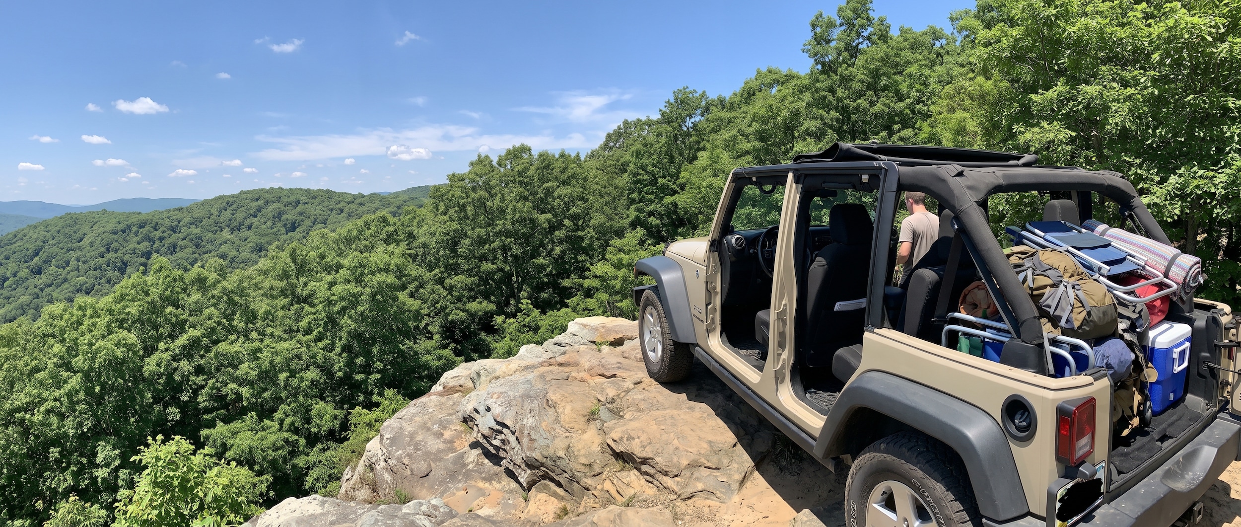Jeep Wrangler Unlimited on a rocky ridge overlook at an Alabama state park in summer with doors off and cargo loaded