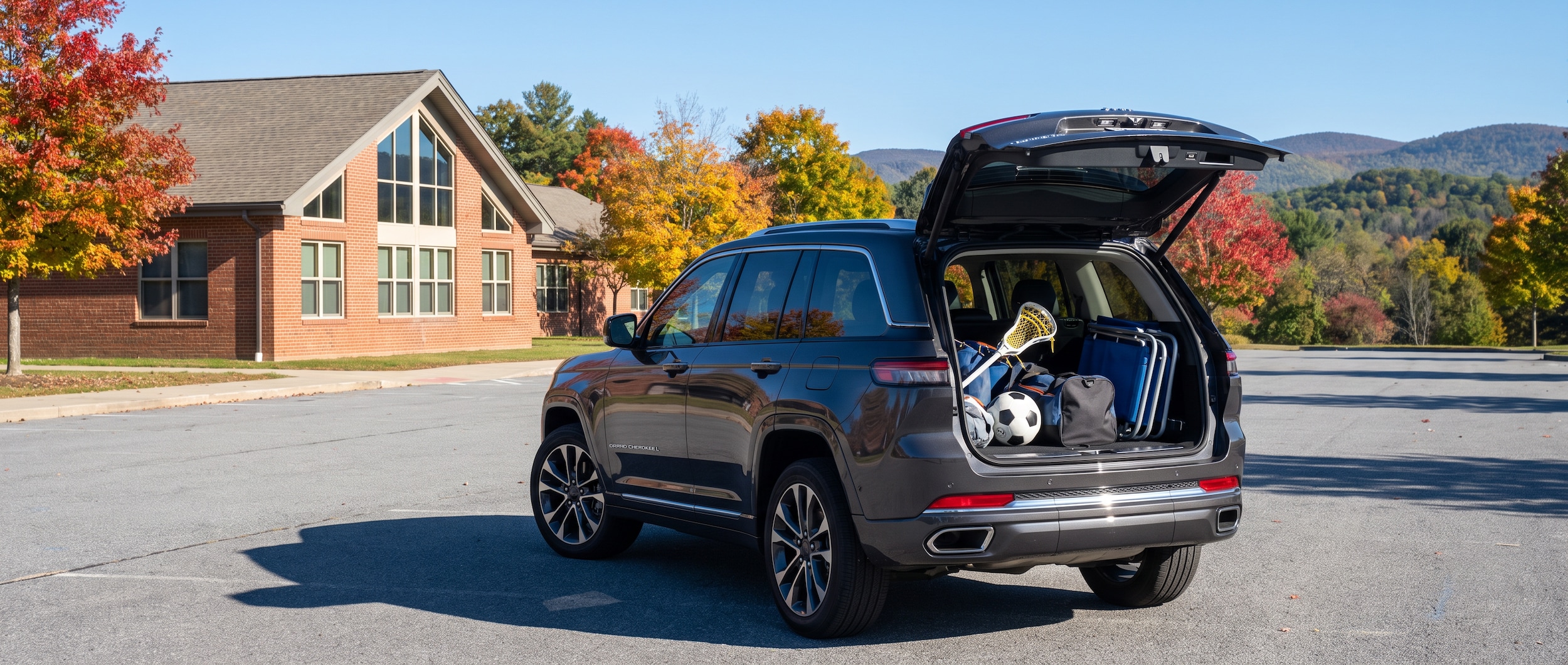 2026 Jeep Grand Cherokee L with hatch open and sports gear loaded, parked outside a Vestavia Hills school on a fall morning