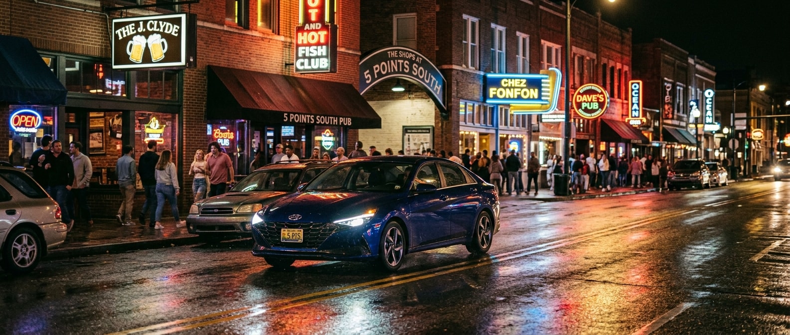 2026 Hyundai Elantra at night on a wet urban street in Birmingham's Southside district with headlights illuminating the road ahead