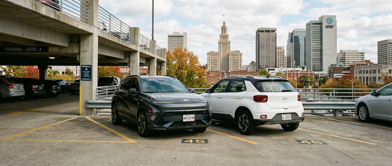 2026 Hyundai Kona and 2026 Hyundai Venue side by side in a downtown Birmingham parking deck, Alabama skyline behind them