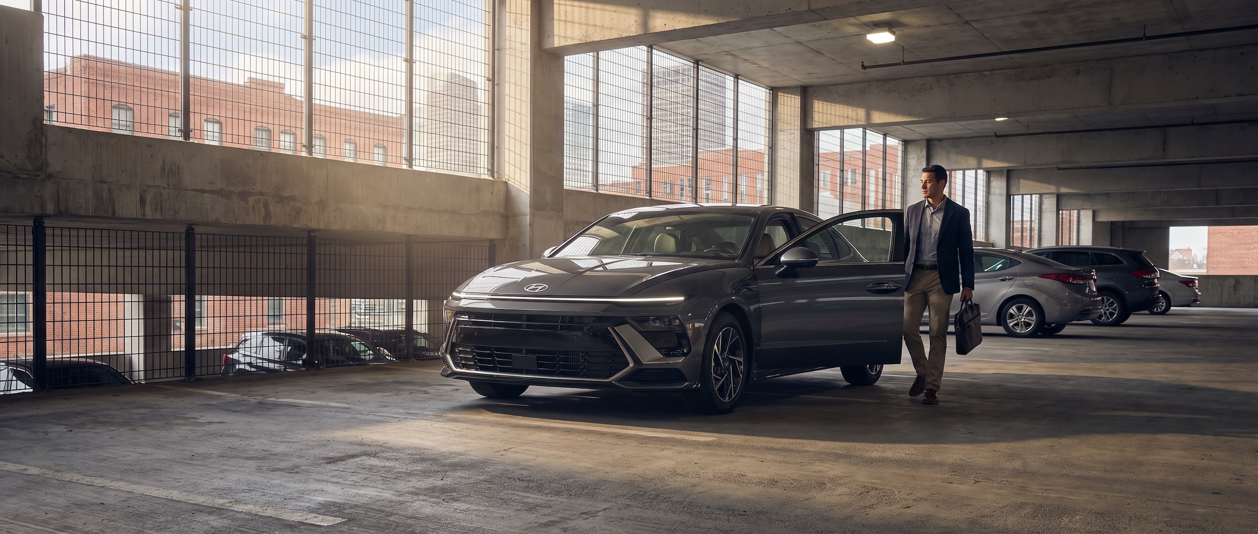 A 2026 Hyundai Sonata SE in a downtown Birmingham parking structure, morning light filtering through concrete levels, conveying a young professional's weekday commute in the city