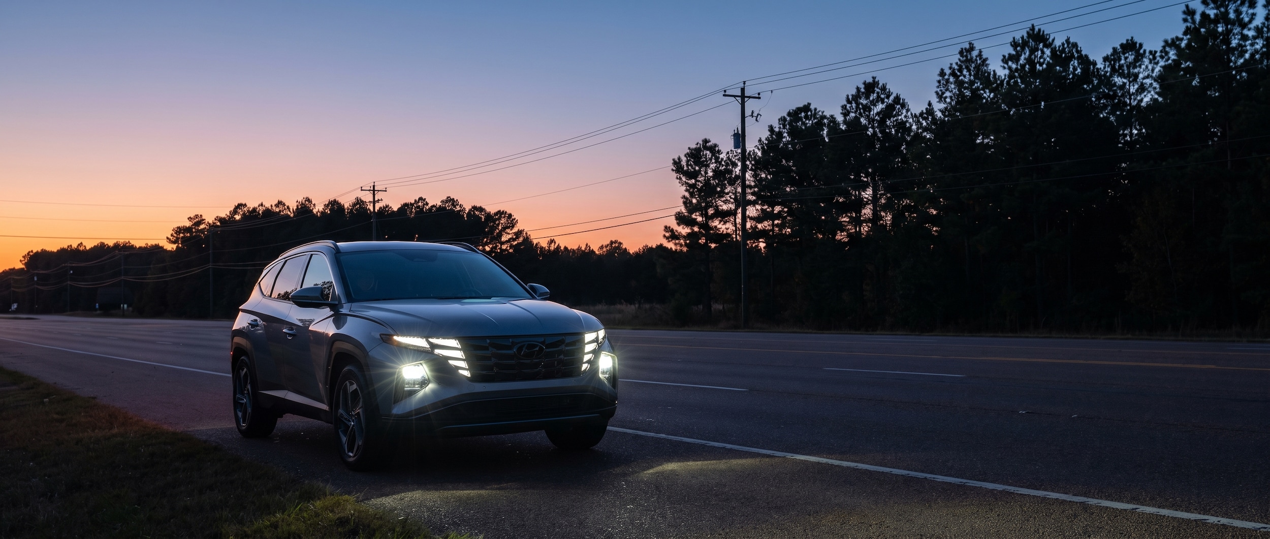 2026 Hyundai Tucson with LED headlights on at dusk on Lakeland Drive in Flowood, Mississippi