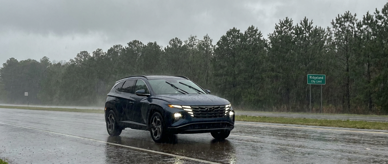 2026 Hyundai Tucson driving in heavy rain on a wet Mississippi road with wipers and headlights on