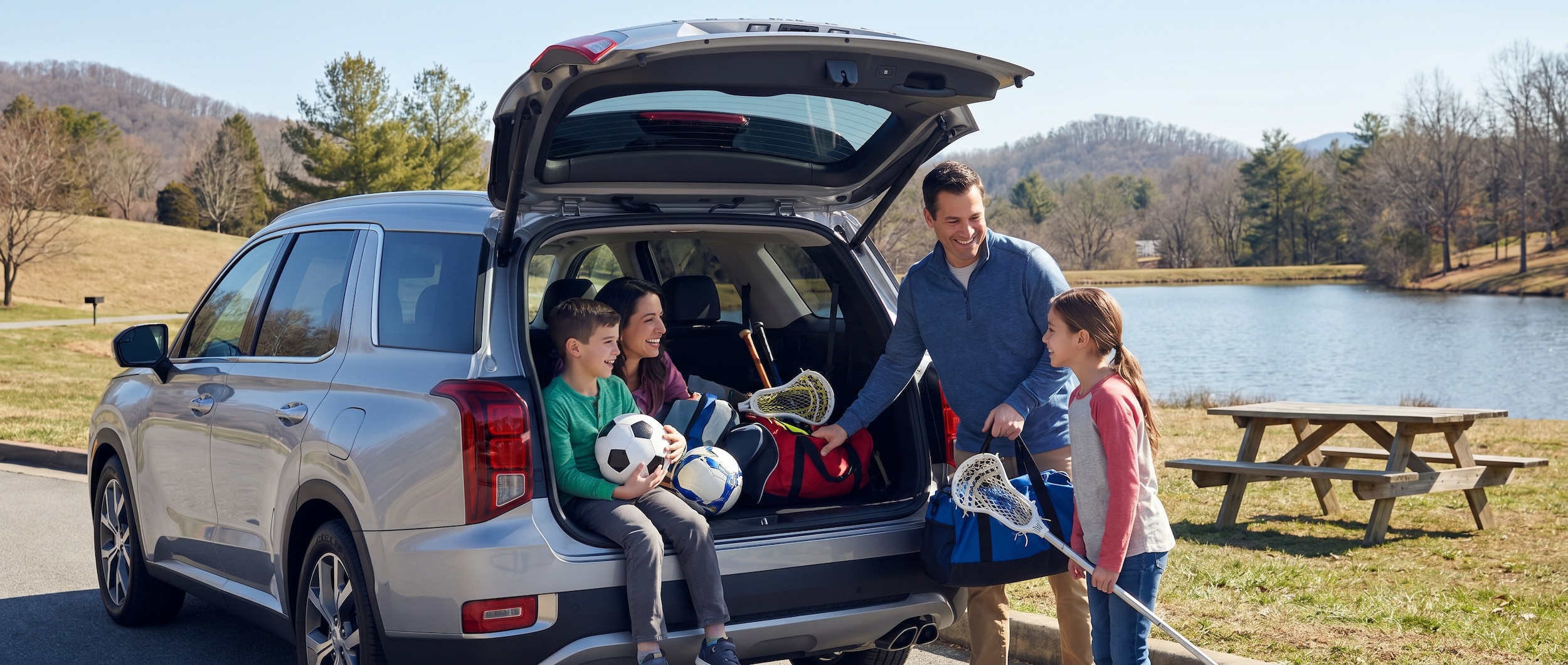 Family loading sports equipment into the back of a three-row SUV at a local Hendersonville park with kids and parents smiling