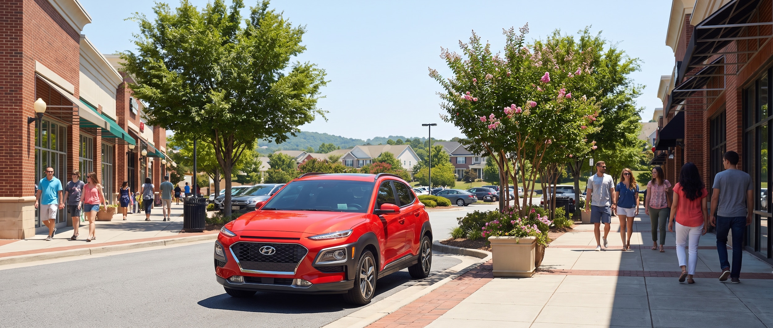 A bright red Hyundai Kona parked in front of a busy outdoor shopping area on a sunny summer day, with blue skies, trees in full leaf, and a relaxed suburban Tennessee backdrop suggesting easy, carefree errand running.